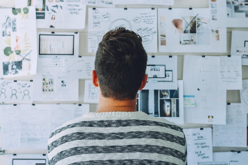 Man seen from behind looking at a board of papers, representing planning and preparing a project